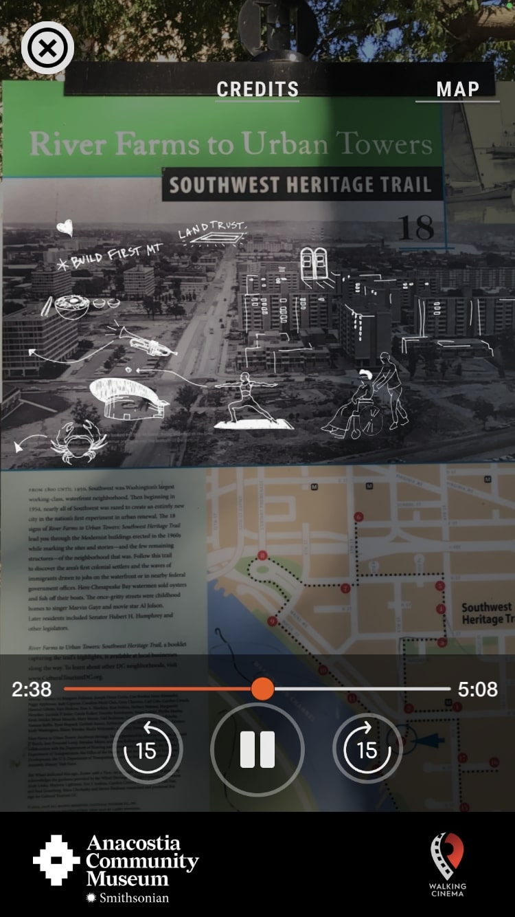 Screenshot of *Before the Bulldozers* app. A phone camera view of a Heritage Trail street sign featuring a large black-and-white aerial photograph of Southwest DC. White line drawing illustrations overlap the image using augmented reality.