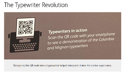 Screenshot showing a brown panel that contains a black typewriter icon with a QR code as the paper on top. Besides the icon is a label that reads “Typewriters in action. Scan the QR code with your smartphone to see a demonstration of the Columbia and Mignon typewriters.” Above the image is the title “The Typewriter Revolution” on the top left corner. There is also a caption below that reads “Designing the QR code into a typewriter helped integrate it into the visitor experience.”