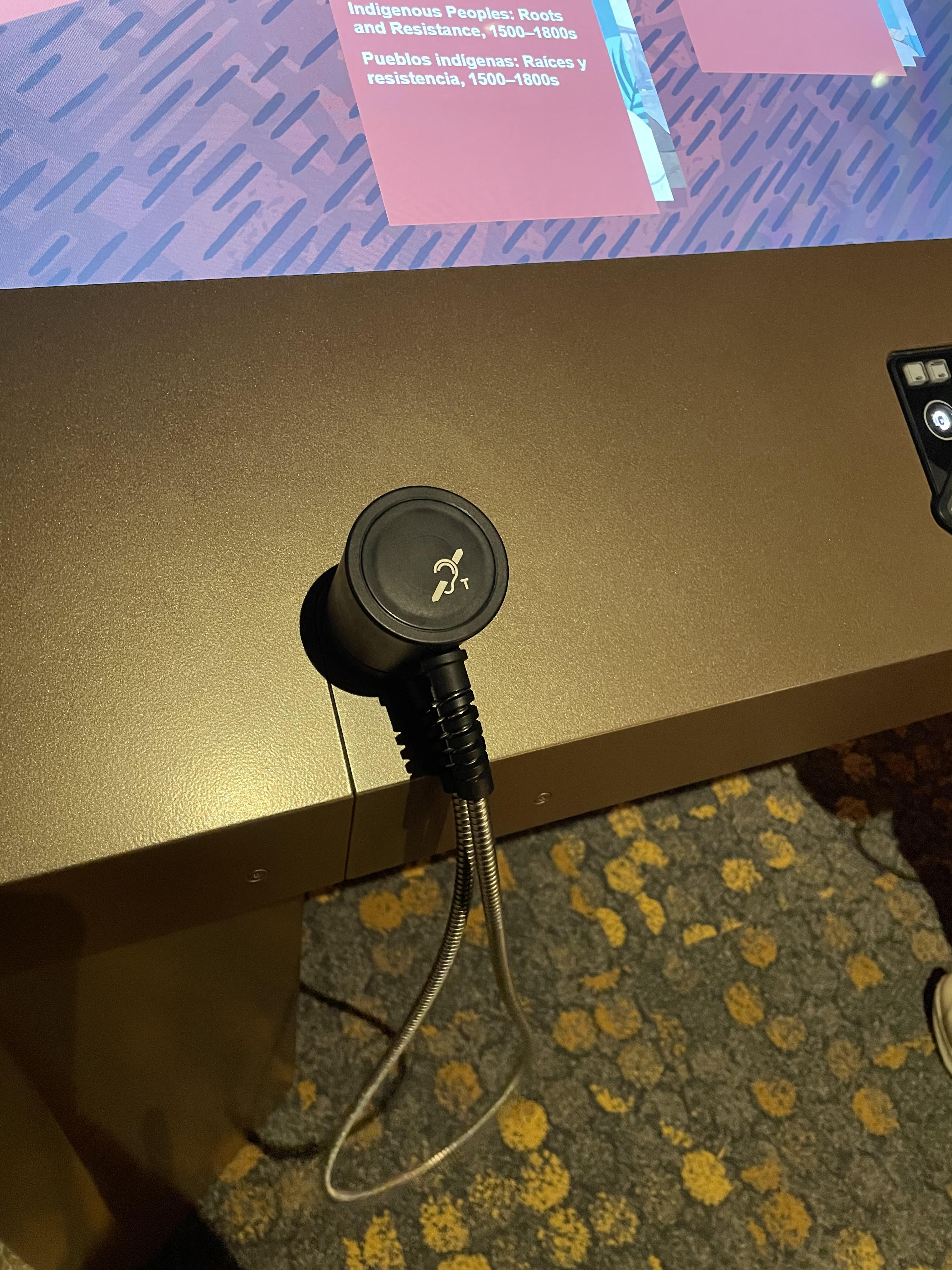 An earphone connected to a digital screen with an induction loop symbol on top